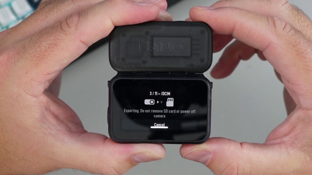 A close-up of the DJI Osmo Nano Vision Dock screen showing "Exporting" status with a warning not to remove the SD card or power off the camera.