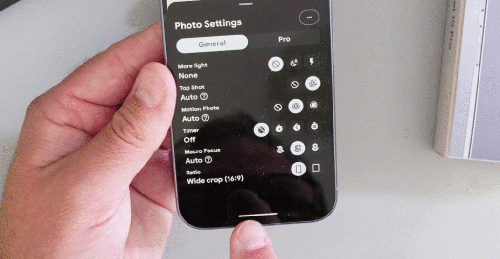 A close-up of a hand holding a Google Pixel 10 Pro smartphone, showing the camera's photo settings menu with the "Ratio" option set to "Wide crop (16:9)".