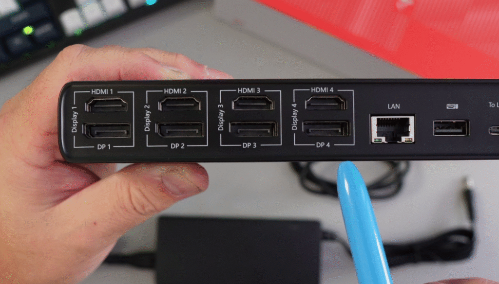 A close-up of the back of the TobenONE UDS050A docking station, highlighting four HDMI ports, four DisplayPort connections, and the Ethernet port, with a blue pen pointing towards the ports.