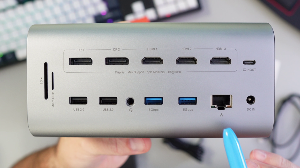 A close-up view of the back panel ports on the silver TobenONE UDS056 20-in-1 Triple 4K docking station, held in hand.
