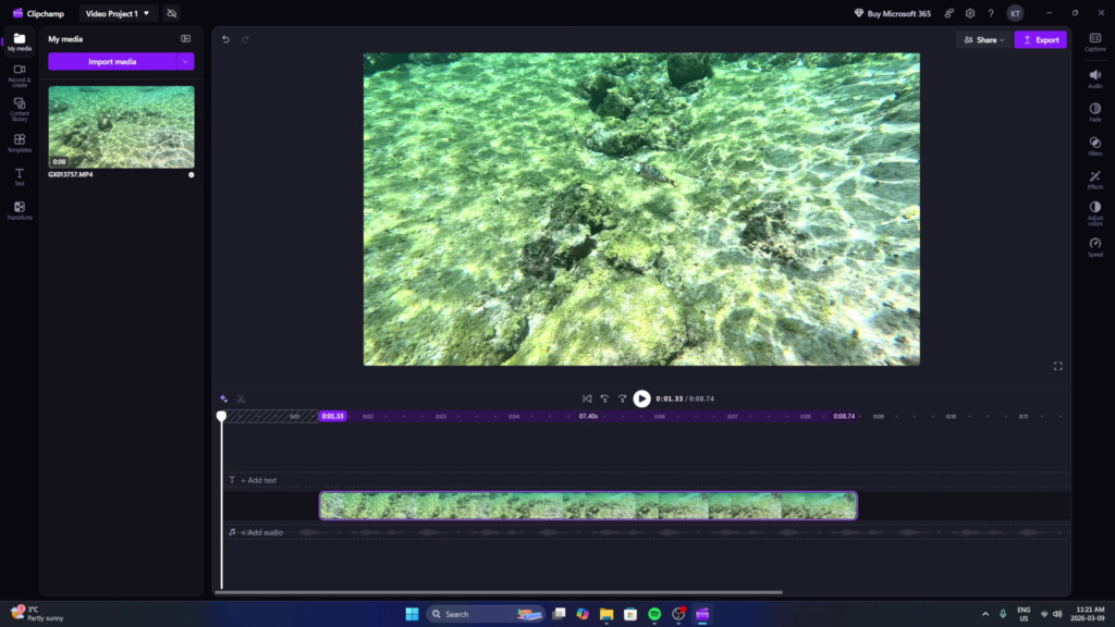 A screenshot of the Microsoft Clipchamp video editor interface on Windows 11, showing an underwater video of tropical fish being trimmed on the timeline using the side handles.