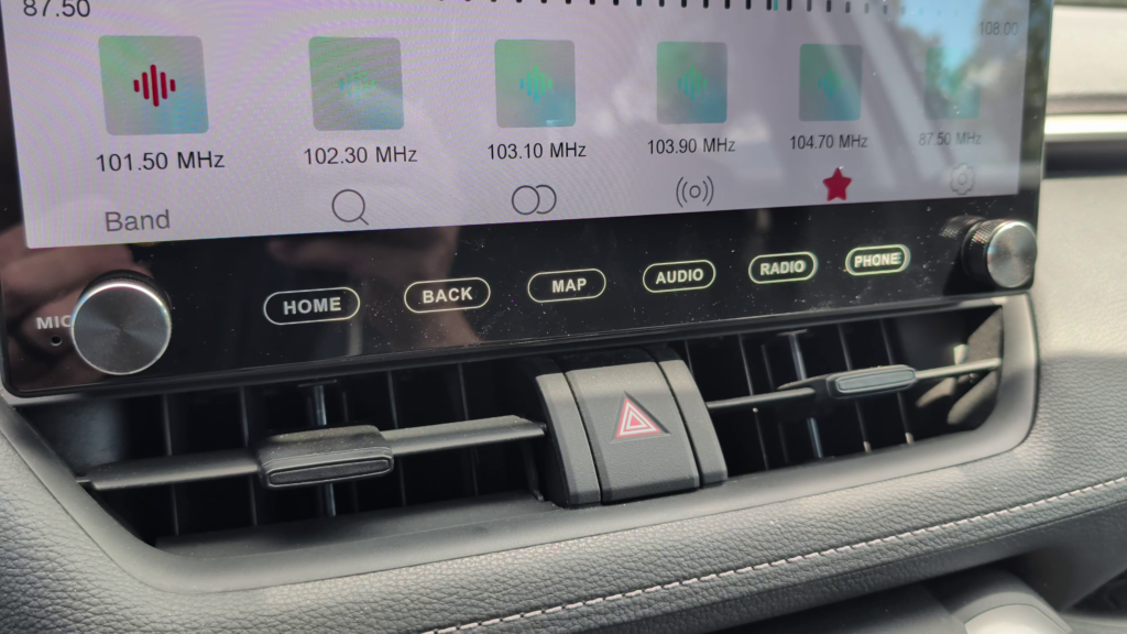 Roadanvi X14 head unit installed in a Toyota RAV4 showing the physical shortcut buttons and volume knob below the touchscreen.
